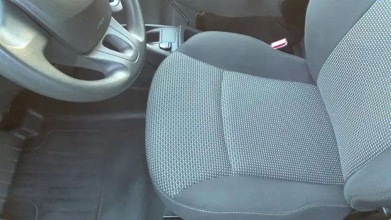 Sedák předního sedadla po vyčištění, šedý vzorovaný potah je jednolitý a bez skvrn, vlevo volant a gumová rohož na podlaze.